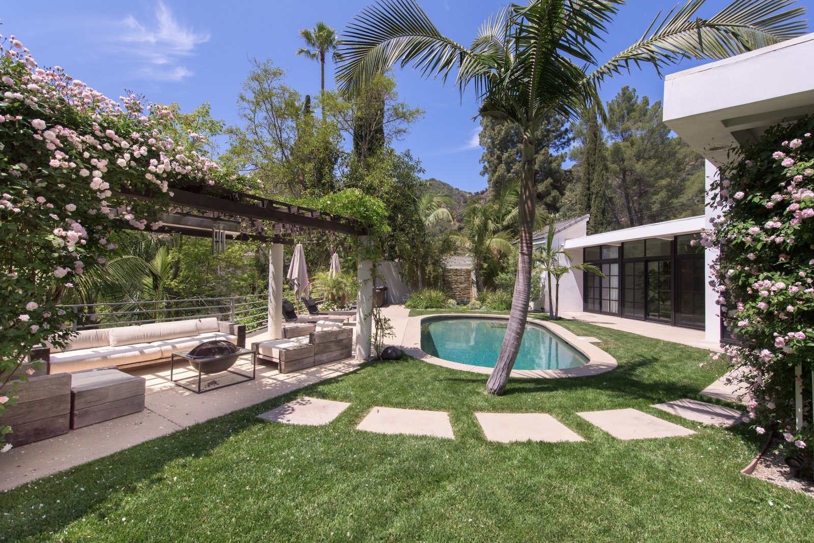 a-small-pool-is-located-just-a-few-steps-away-from-the-living-room-a-flower-covered-trellis-offers-a-canopy-for-alfresco-dining-and-lounging