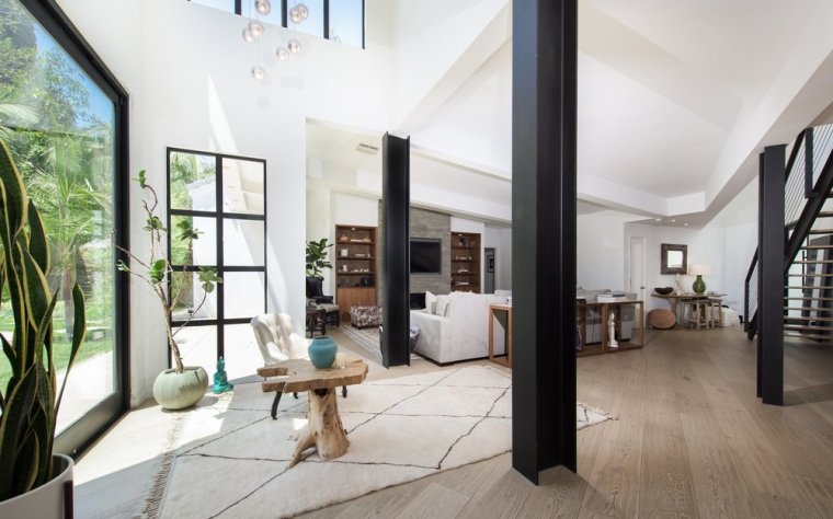 the-airy-living-roomtucked-underneath-a-vaulted-ceilingflows-between-the-kitchen-and-dining-areas-a-staircase-leads-to-a-voluminous-double-height-gym